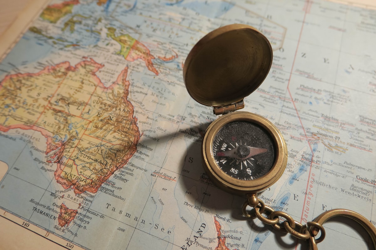 A compass resting on an open map, oriented toward a direction