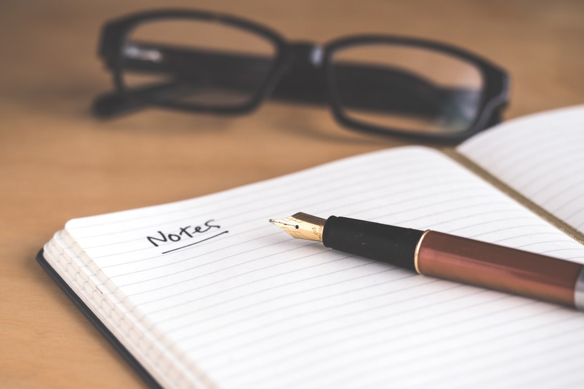 A handwritten letter and fountain pen resting on an old wooden desk, soft window light