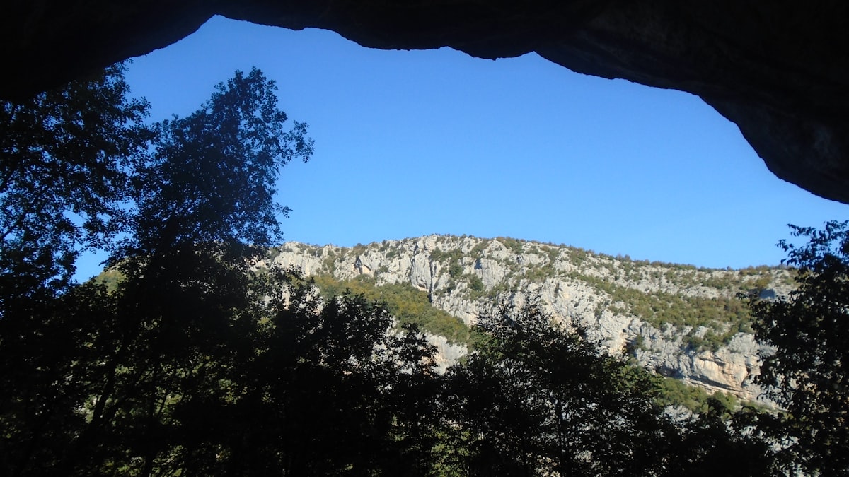 A mountain valley framed through a cave opening